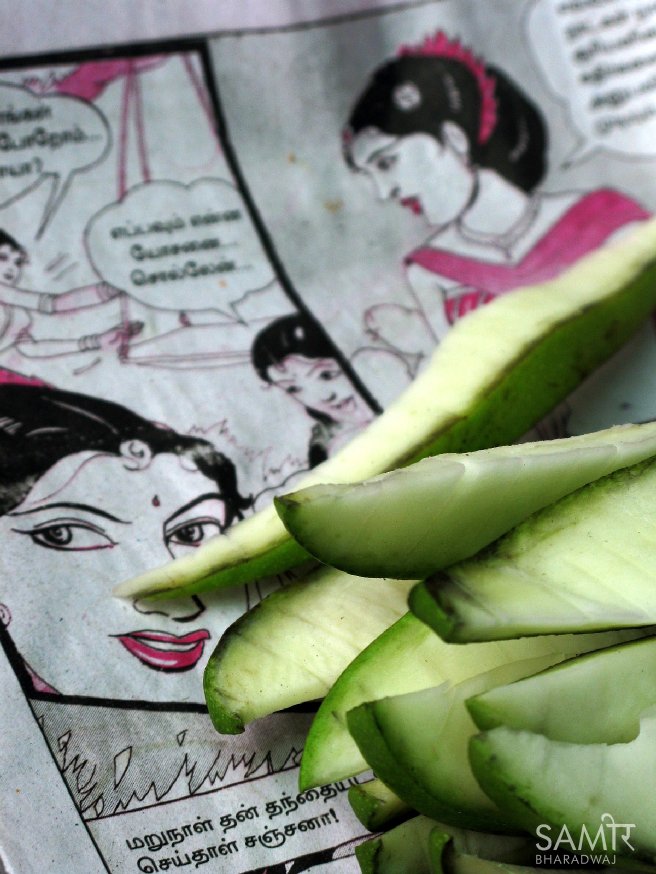 Slices of raw mango on sale placed on an old page of Tamil comics